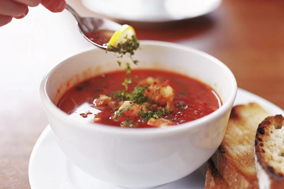 Close-up of Seafood Cioppino Gremolata in a bowl with steaming tomato broth and fresh gremolata