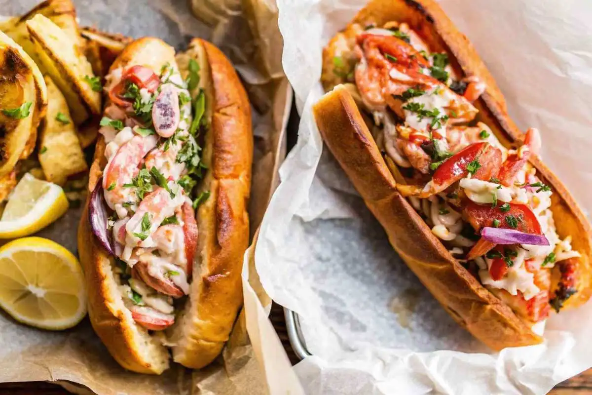 Classic lobster roll with chips and lemon on a white plate, representing East Coast cuisine