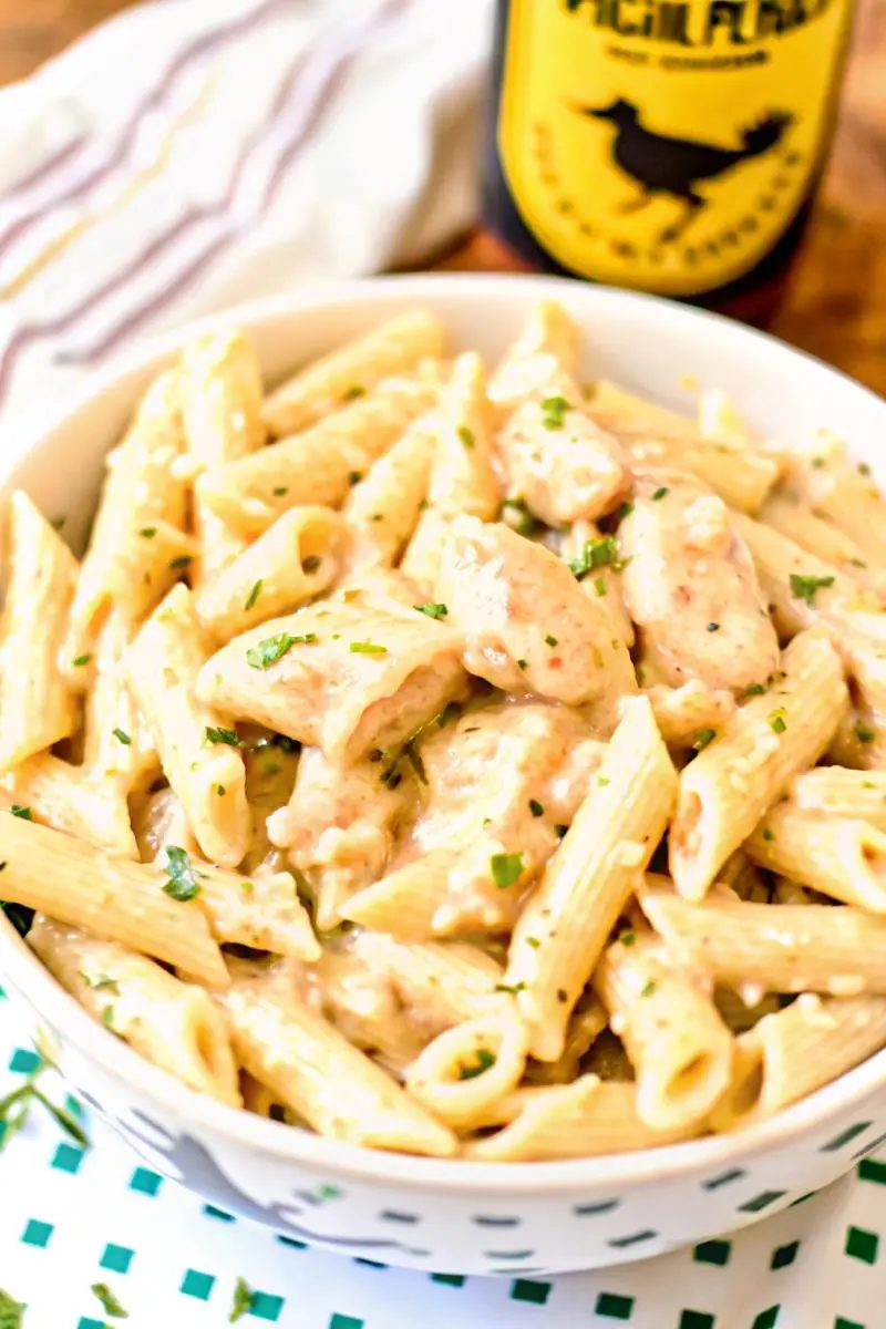 Creamy chicken penne pasta garnished with fresh parsley in a white bowl